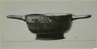 Two-handled black-glazed bowl with a low ring foot, shown in side view against a pale background