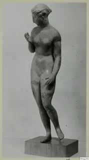 Standing female nude statue in stone, shown on a wooden block base against a plain grey background