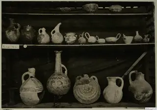 Shelves of pottery vessels, jugs and bowls from Lapithos, with a label reading Lapithos on the middle shelf