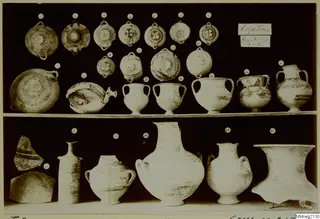 Shelved group of numbered pottery vessels from Lapithos Markides Tomb 2, including bowls, jugs and large jars.
