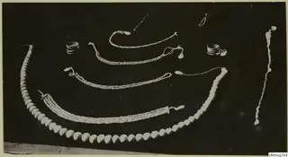 Necklaces, rings and bracelets of pale beads laid out on a dark background