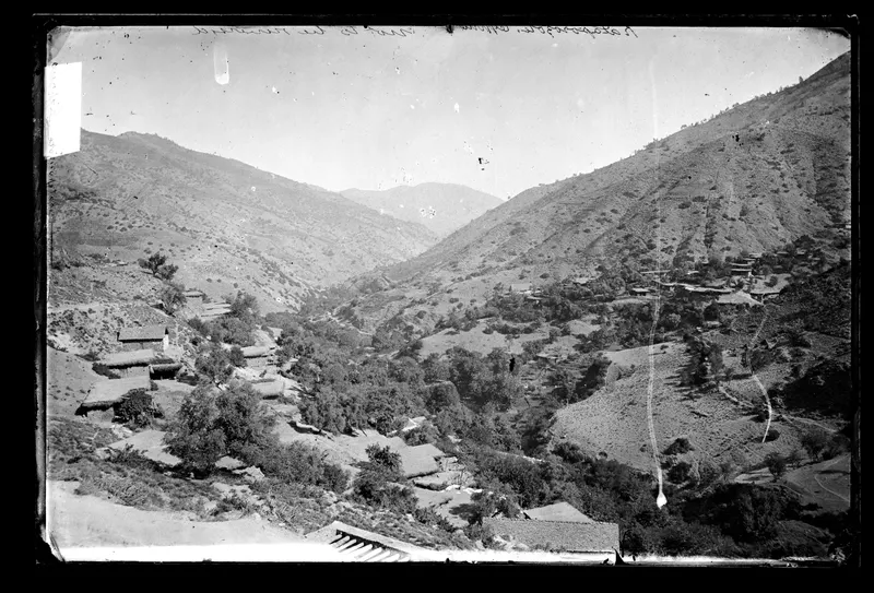 Steep valley with clusters of village houses on the hillsides and trees along the valley floor
