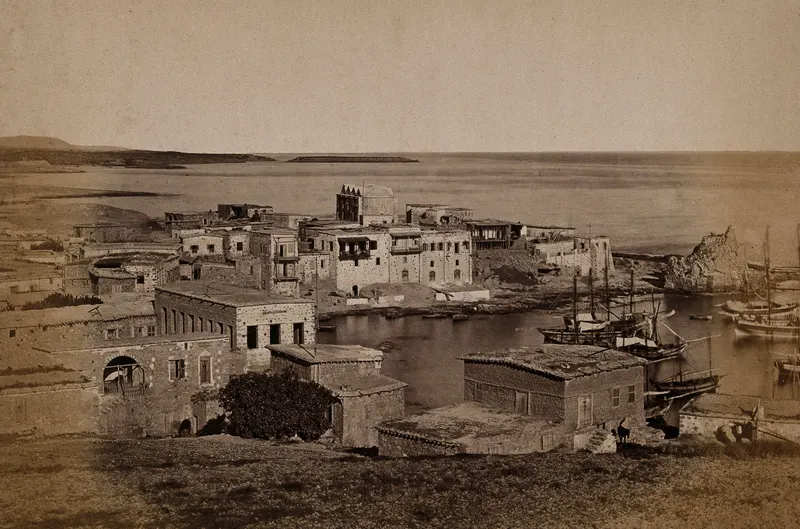 Stone buildings along a harbour at Kyrenia, with sailing boats moored on the right and the sea beyond.