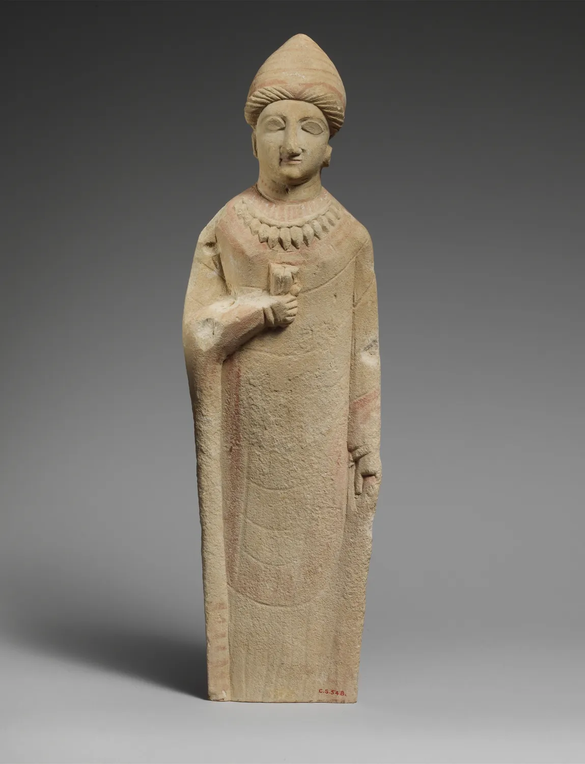 Cypriot limestone female votary in a long robe and a tall headdress, holding a flower offering; Archaic period, Cesnola Collection, the Metropolitan Museum of Art.