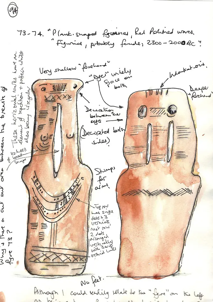 A sketchbook page with watercolour studies of the two Brew plank figures, annotated in pencil with observations ('very shallow forehead', 'eyes widely spaced on both', 'stumps for arms', 'no feet') and the copied gallery label, 'Figurine, probably female, 2300–2000 BC'. (Ann Kelcey)