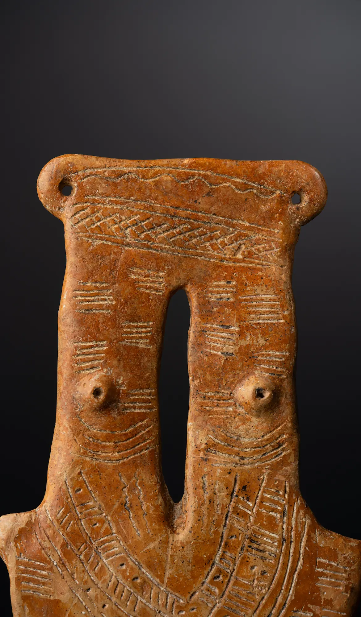 Close view of the two-necked figure's chest: the two necks bridged at the top, a small pellet breast with a punched nipple to either side, and the deep slot cut down the centre between them. (Drakopoulos collection)