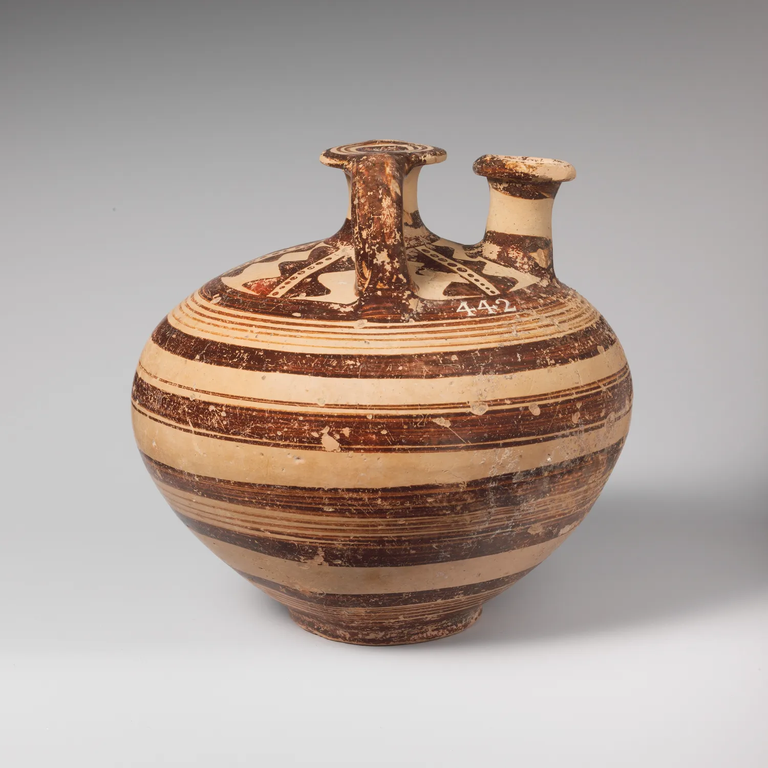 A Mycenaean stirrup jar from the Cesnola Cypriot collection, banded in lustrous brown with a closed false spout and an offset pouring spout, the kind of imported Aegean vase found in Late Bronze Age harbour towns on Cyprus. Metropolitan Museum, New York.