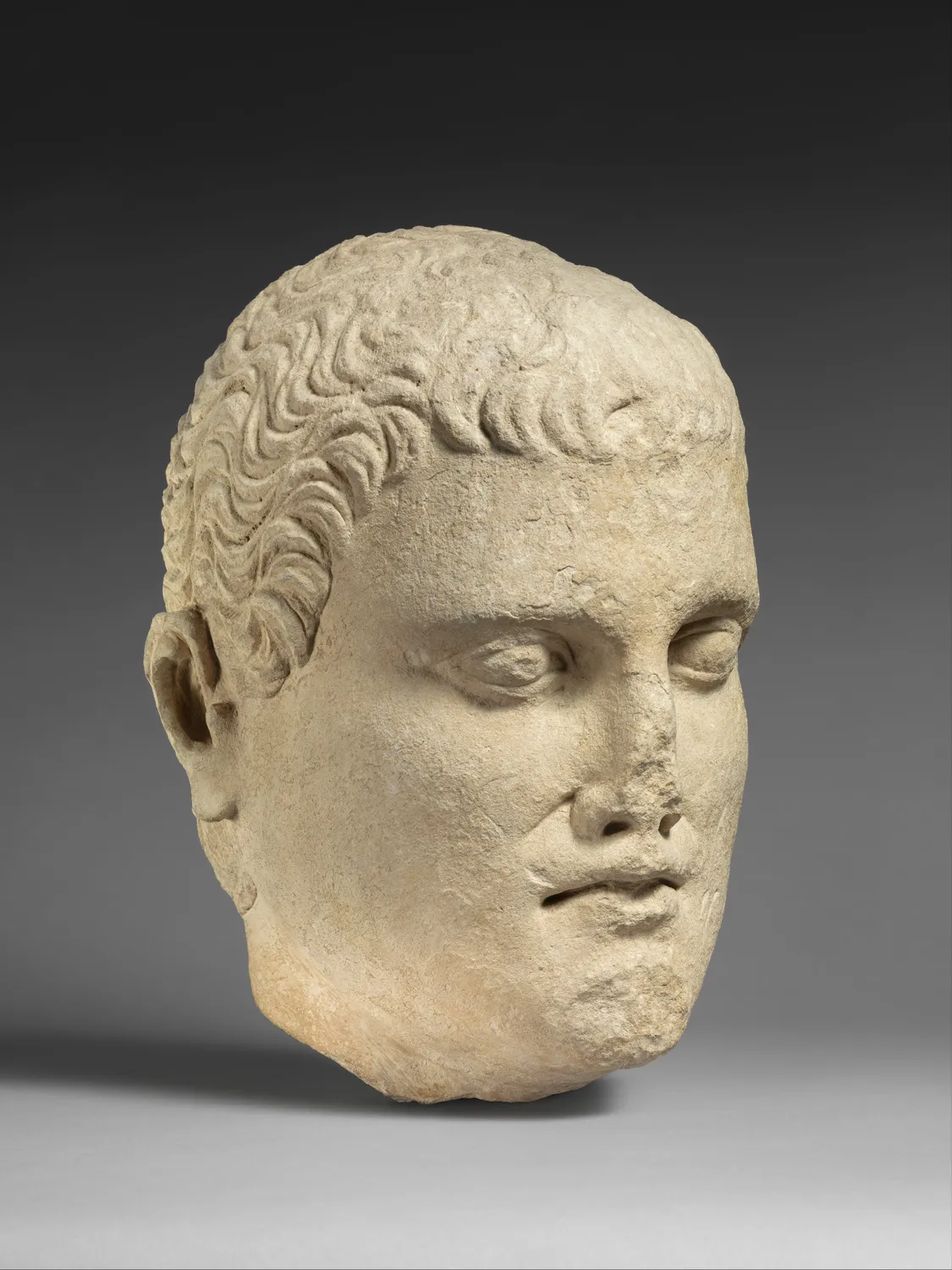 Limestone head of a beardless young man, broken at the neck, from the Cesnola Collection at the Metropolitan Museum.