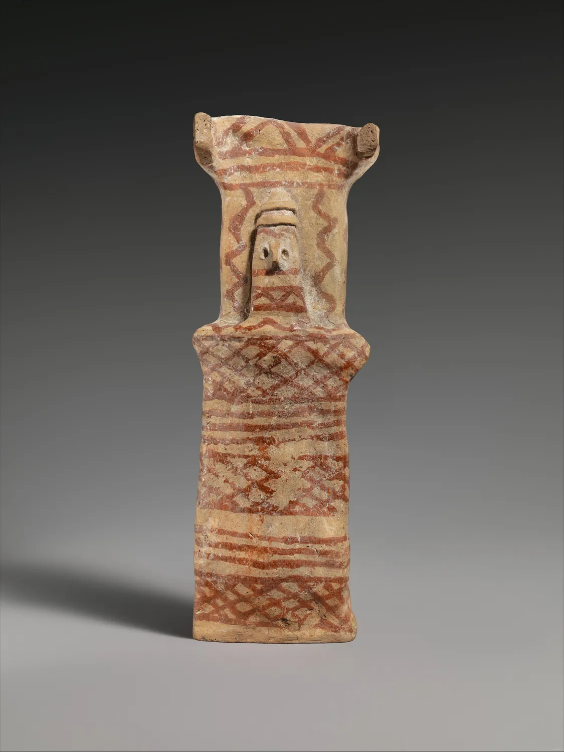 Cypriot terracotta model of an infant swaddled in a tall rectangular cradle painted with red linear bands, of the same Middle Bronze Age type as the Hadjiprodromou cradle.
