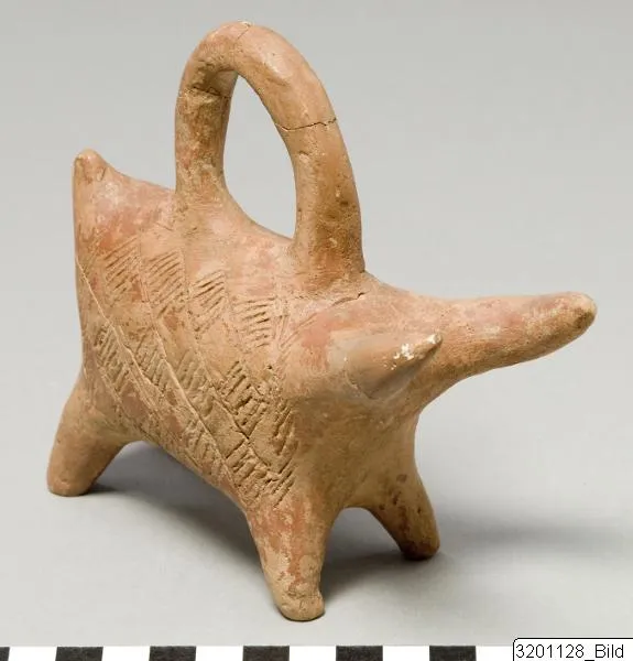A small Red Polished animal askos with a long head, a tall loop handle, and bands of incised herringbone running down the flank, standing on four legs. Medelhavsmuseet, Stockholm, L. 315b-c:022.