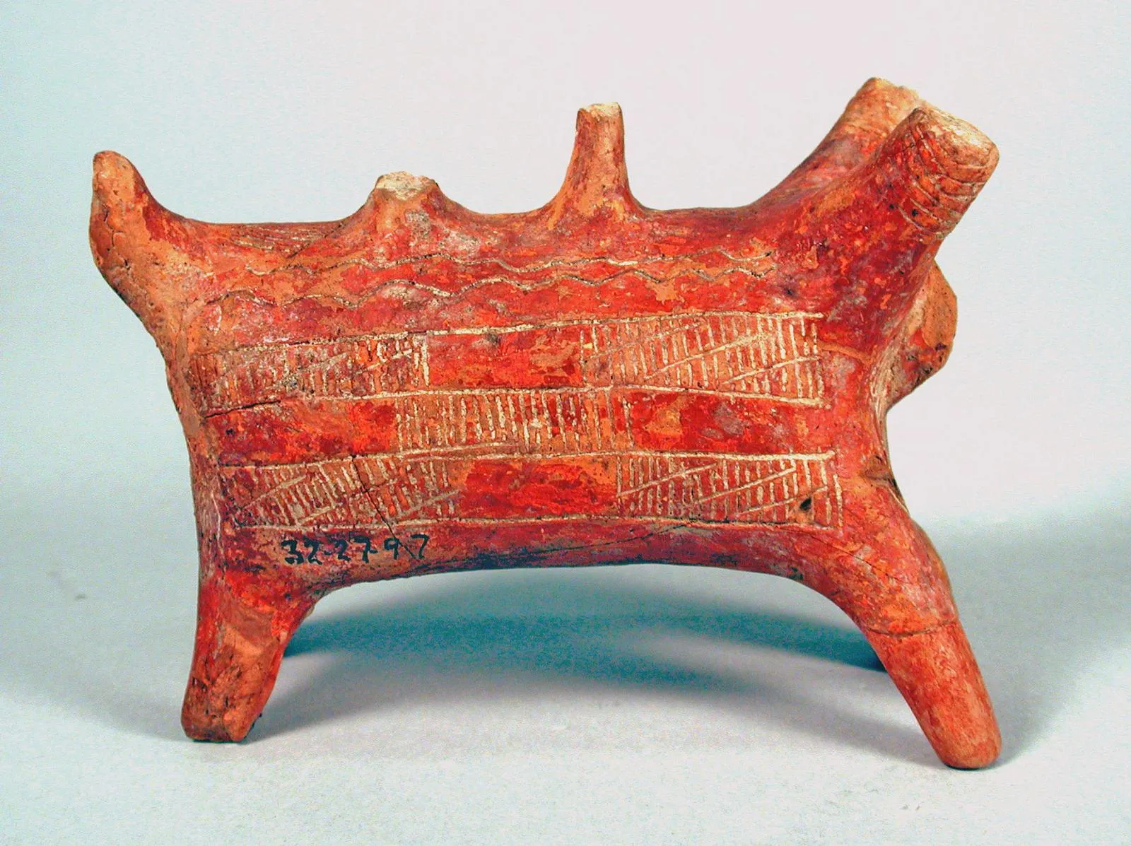 A Red Polished zoomorphic vessel from Cyprus with a head and spout at one end, two projections rising from the back, four legs, and bands of incised hatching on the body. Penn Museum, 32-27-97.