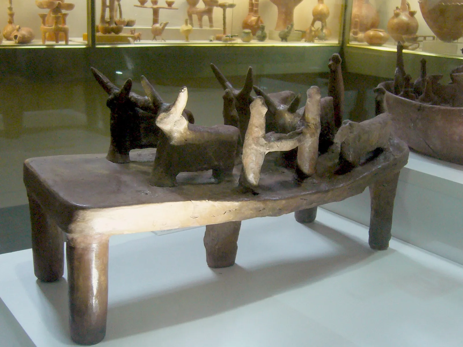 A Bronze Age terracotta model from a tomb at Bellapais-Vounous showing pairs of horned oxen yoked to ploughs with human figures behind them, all set on a rectangular base.