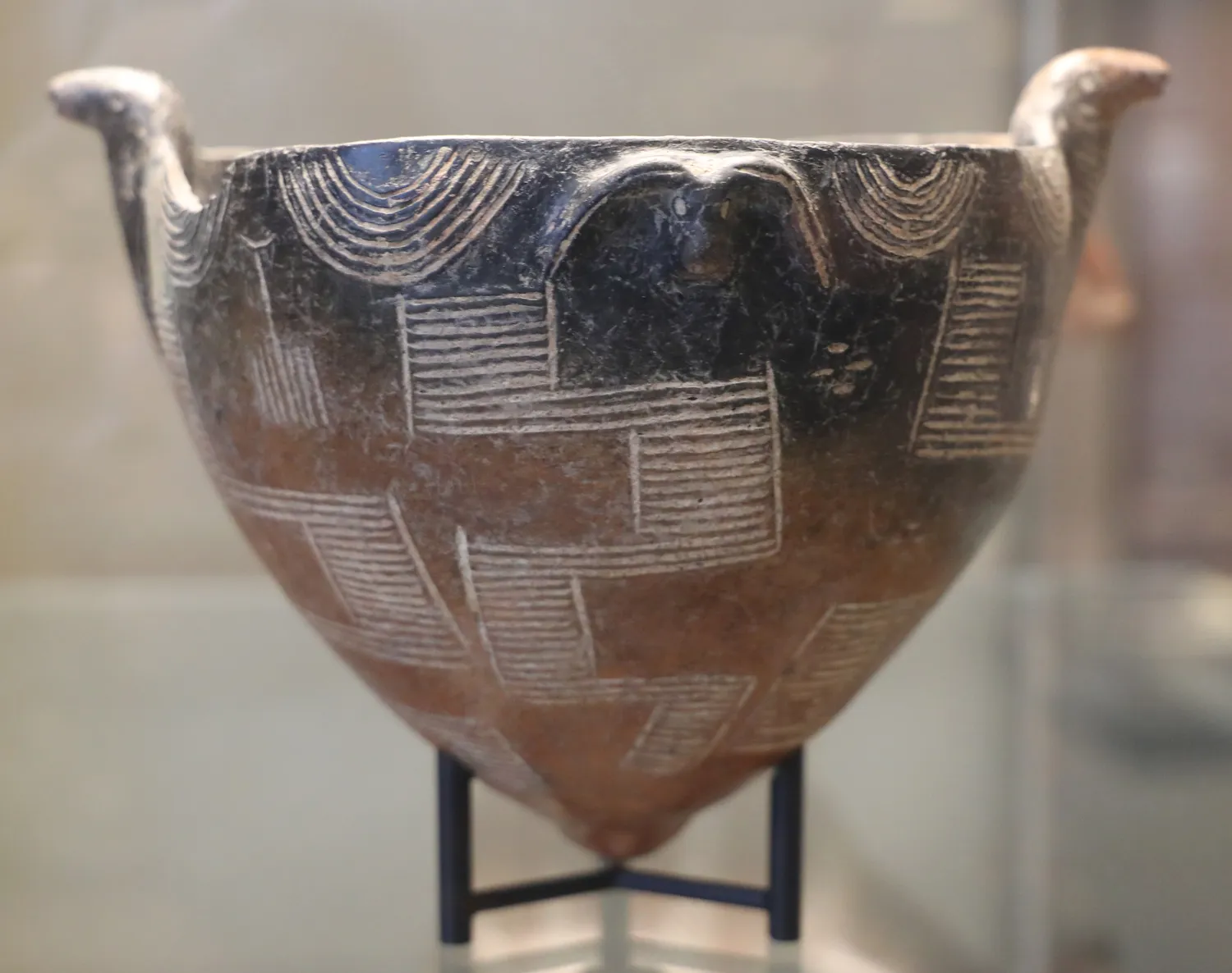 A deep Red Polished tulip bowl from Vounous, its upper third fired black, two small bird heads modelled at the rim and the body covered in white-filled incised hatching. Louvre, AM 2732 (photo Francesco Bini, CC BY-SA 4.0).