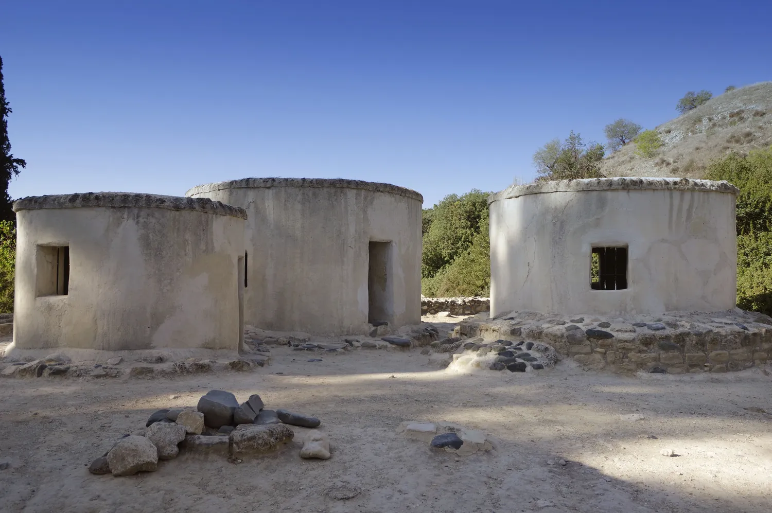 Three of the replica houses at Khirokitia, built in the 1990s: plastered round rooms under flat earth roofs. They are modern reconstructions. Photo: Berthold Werner, CC BY-SA 4.0.