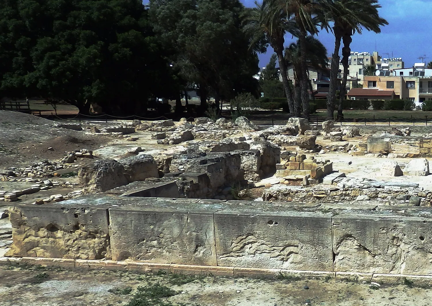 An ashlar wall of Temple 1 at Kition-Kathari, from the rebuilding of around 1200 BC: a row of tall dressed slabs (orthostats) standing on a low plinth course. Everything that stood above them is gone. Photo: Hermann Junghans, CC BY-SA 3.0 DE.