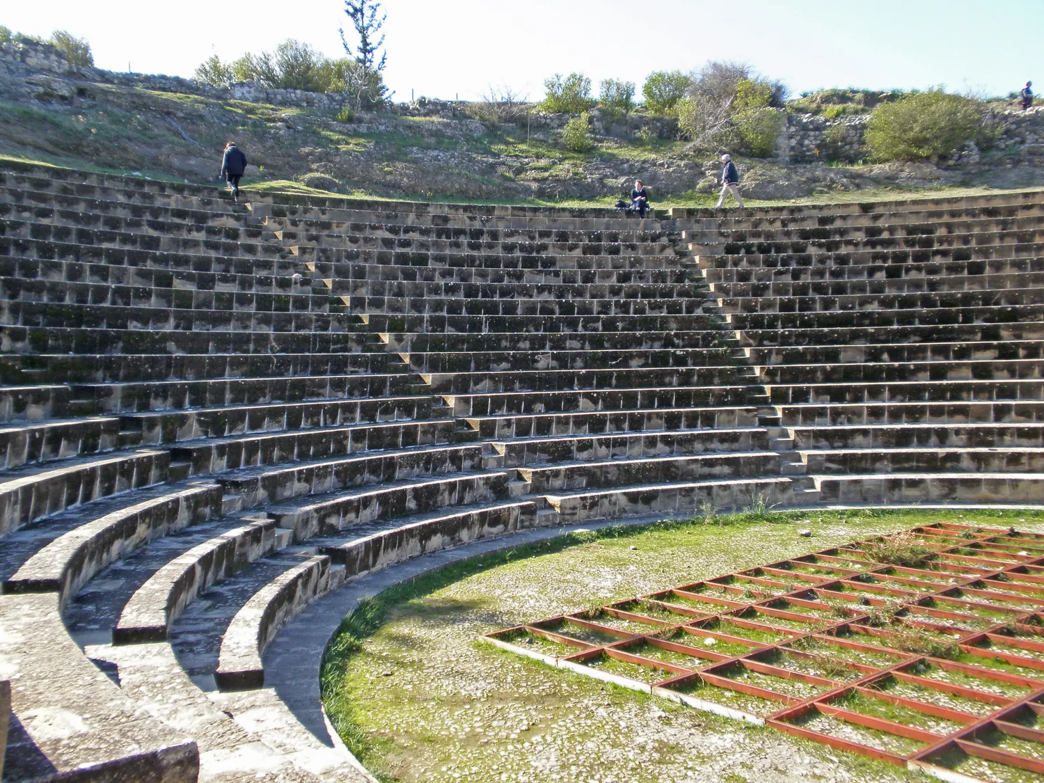 The theatre at Soli as rebuilt from 1962: rows of squared limestone seats with crisp edges and even joints curve round a grassed orchestra, with a modern grid laid over part of it in the foreground. Photo: Amanda Slater, CC BY-SA 2.0.