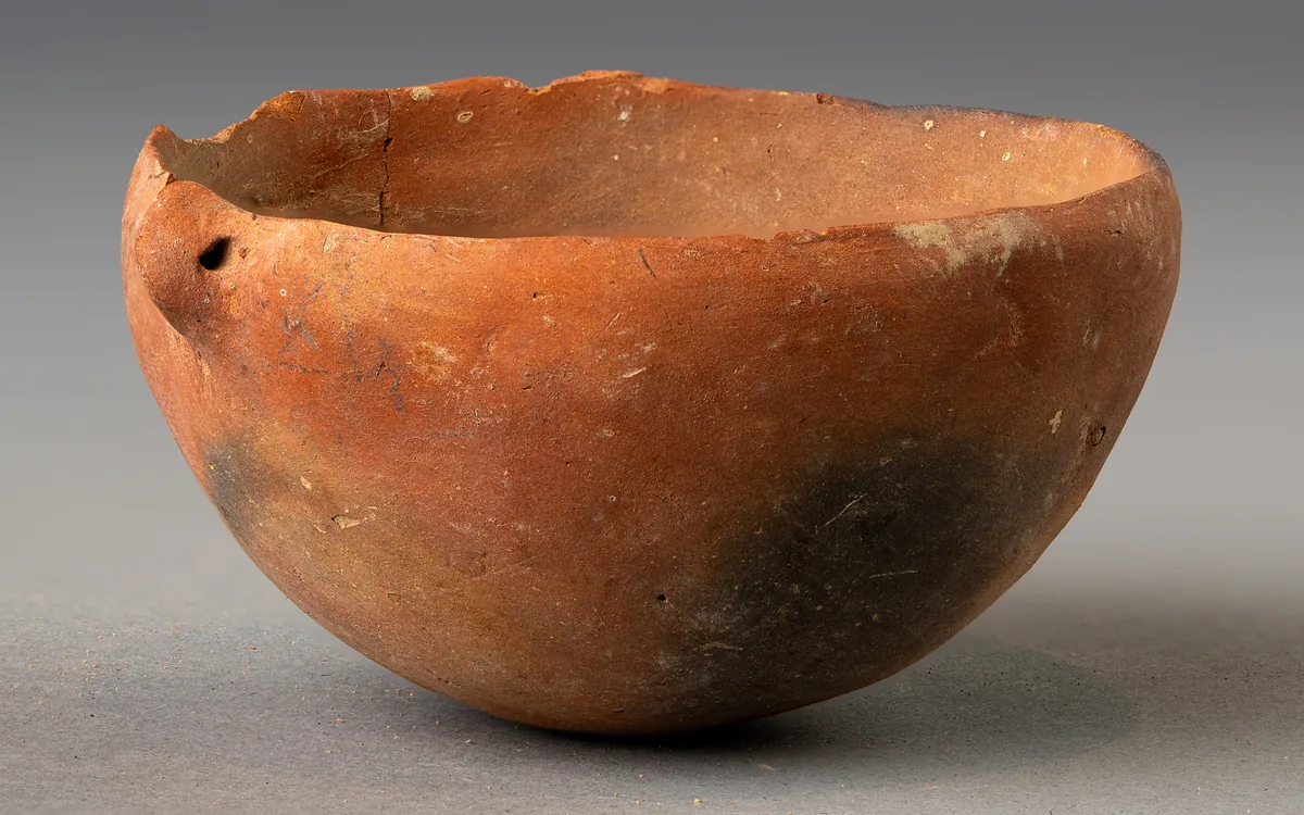 Small Red Polished Bowl with Pierced Lug and Fire-Cloud
