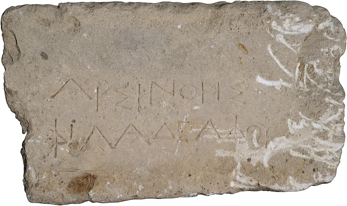 Rough rectangular limestone block with two lines of incised Greek capitals, the right side crusted with white deposit