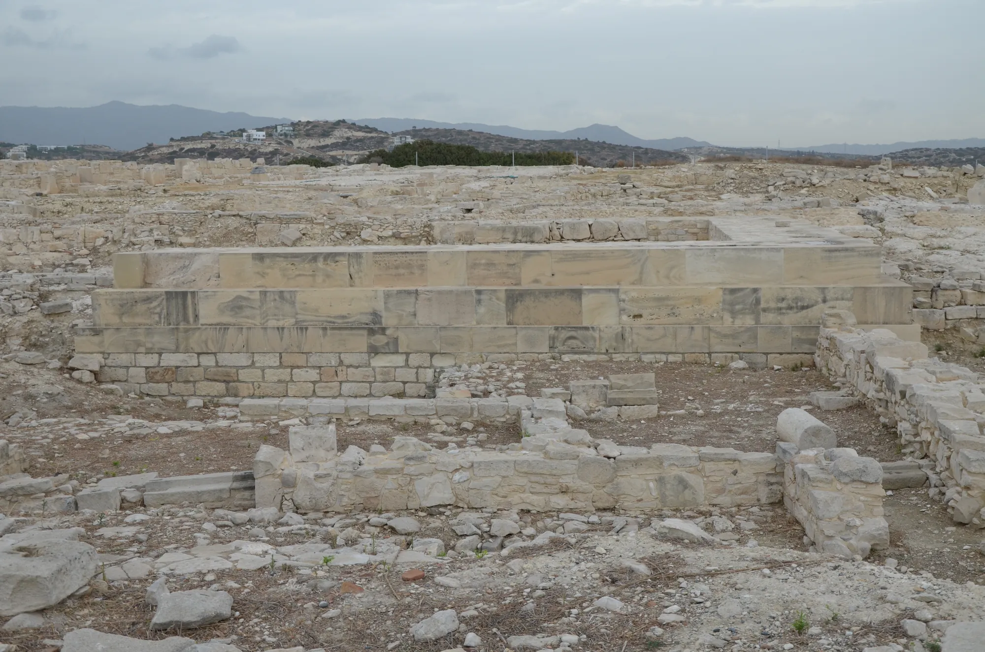 Courses of large squared limestone blocks forming a temple foundation among rubble