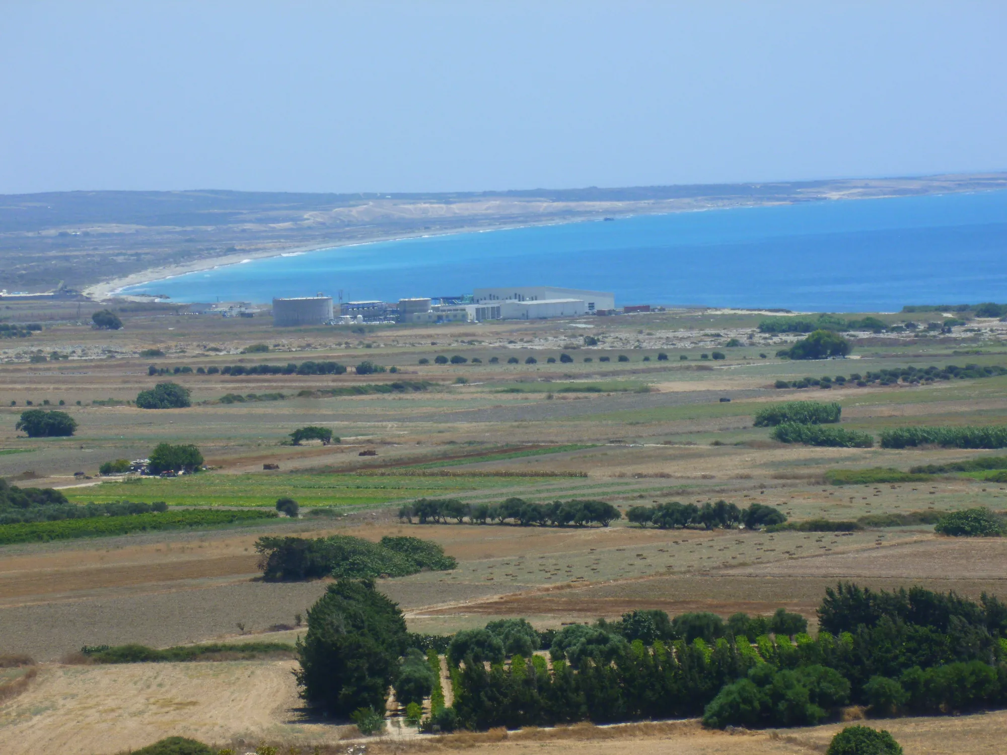 A wide coastal plain of fields and a long curving bay, seen from a height