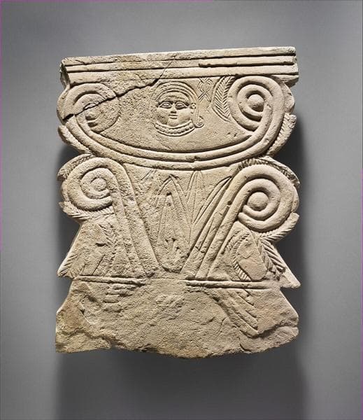 Limestone funerary stele with volutes and a Hathor head