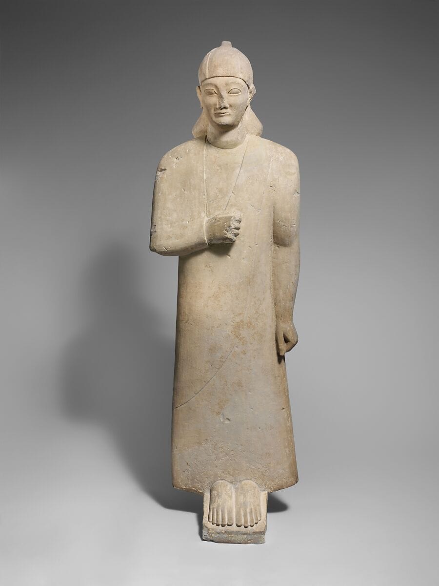 Limestone votary of a beardless male wearing a long garment and a conical helmet, Archaic II Cypriot statue