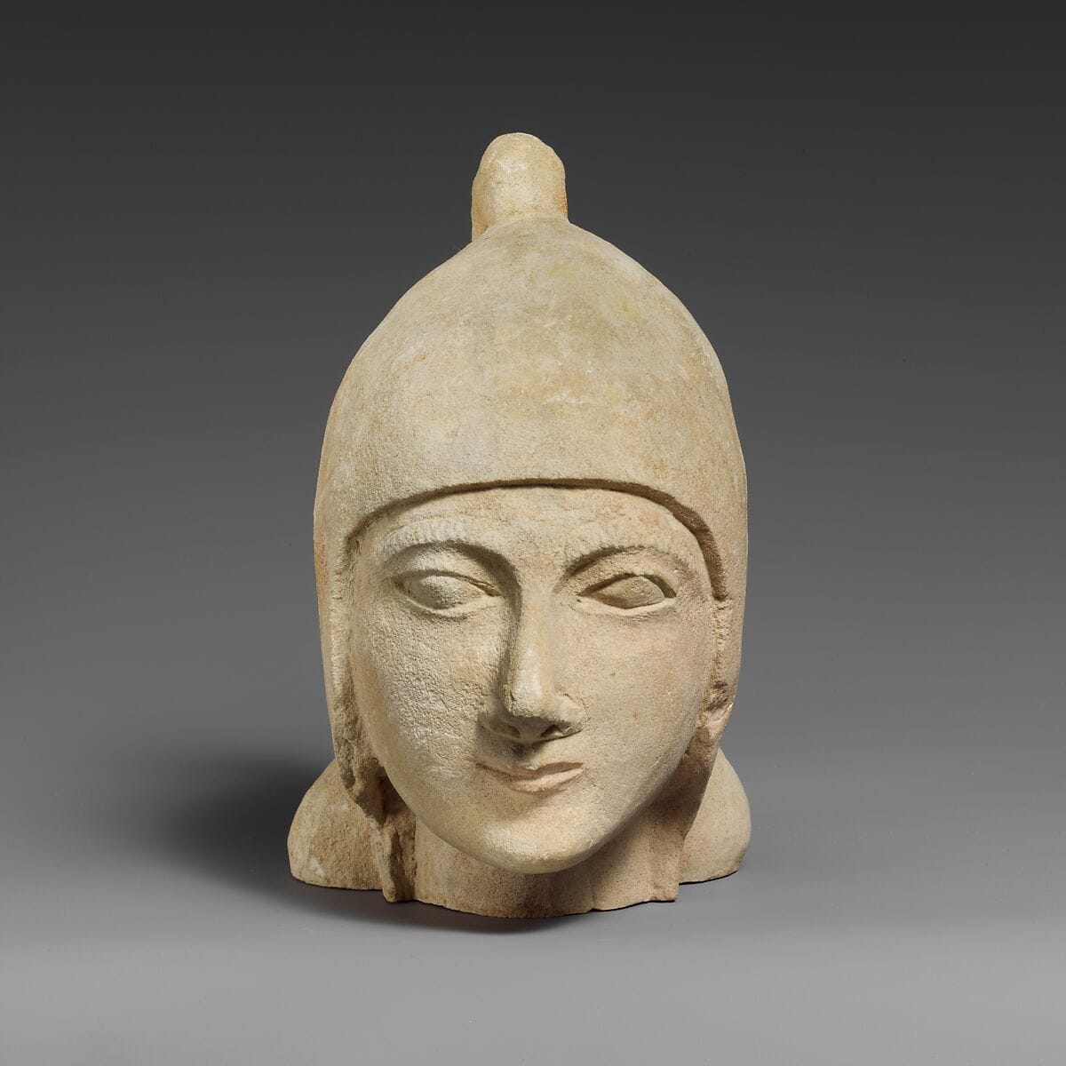 Limestone head of a beardless male wearing a conical helmet, Archaic II Cypriot statue