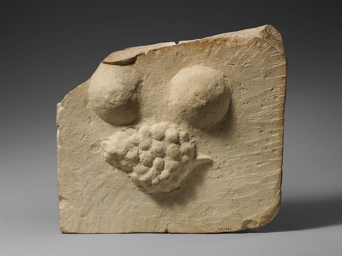 Limestone plaque with breasts and a bunch of grapes in relief, Hellenistic Cypriot