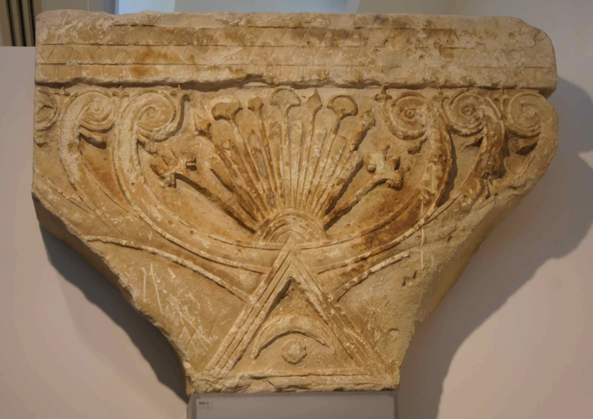 A carved limestone capital with spiral volutes and a fan-shaped palmette