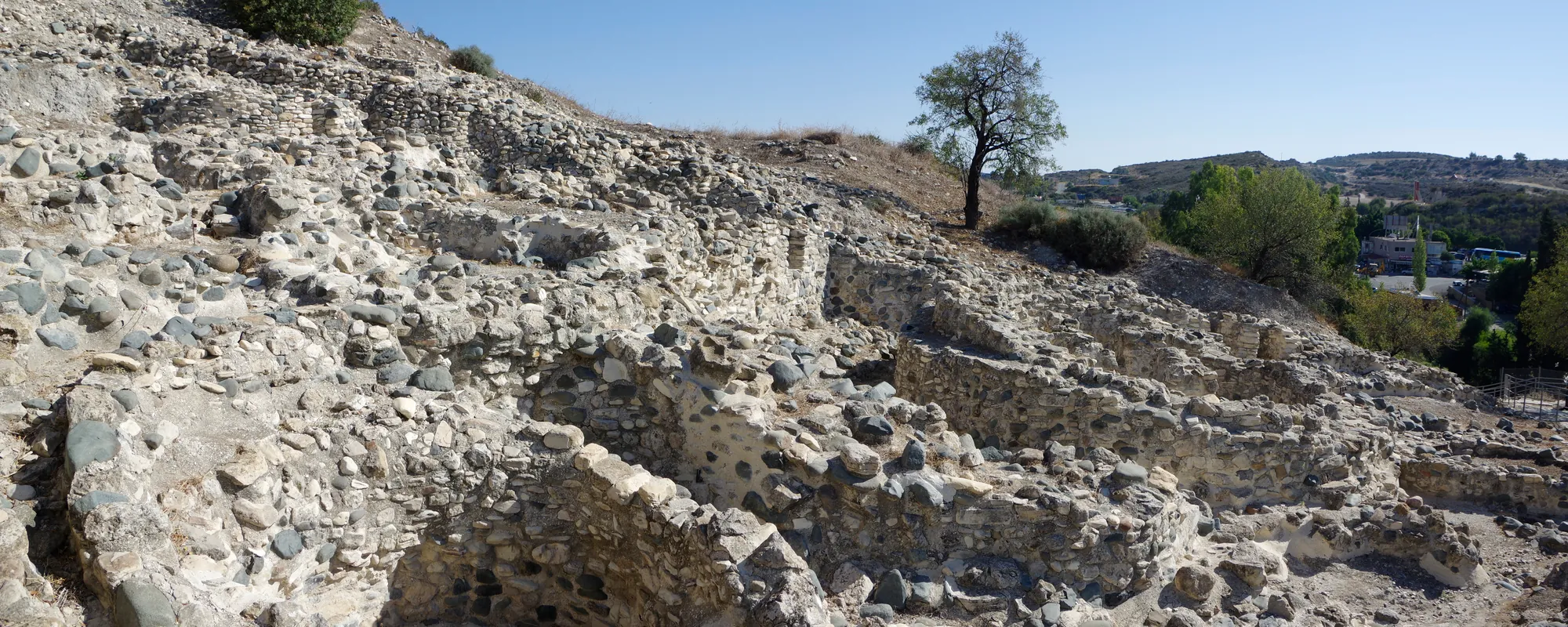 The excavated round houses of Khirokitia rising in tiers up the hillside, their walls of river cobbles and rubble. Photo: Berthold Werner, CC BY-SA 4.0, via Wikimedia Commons