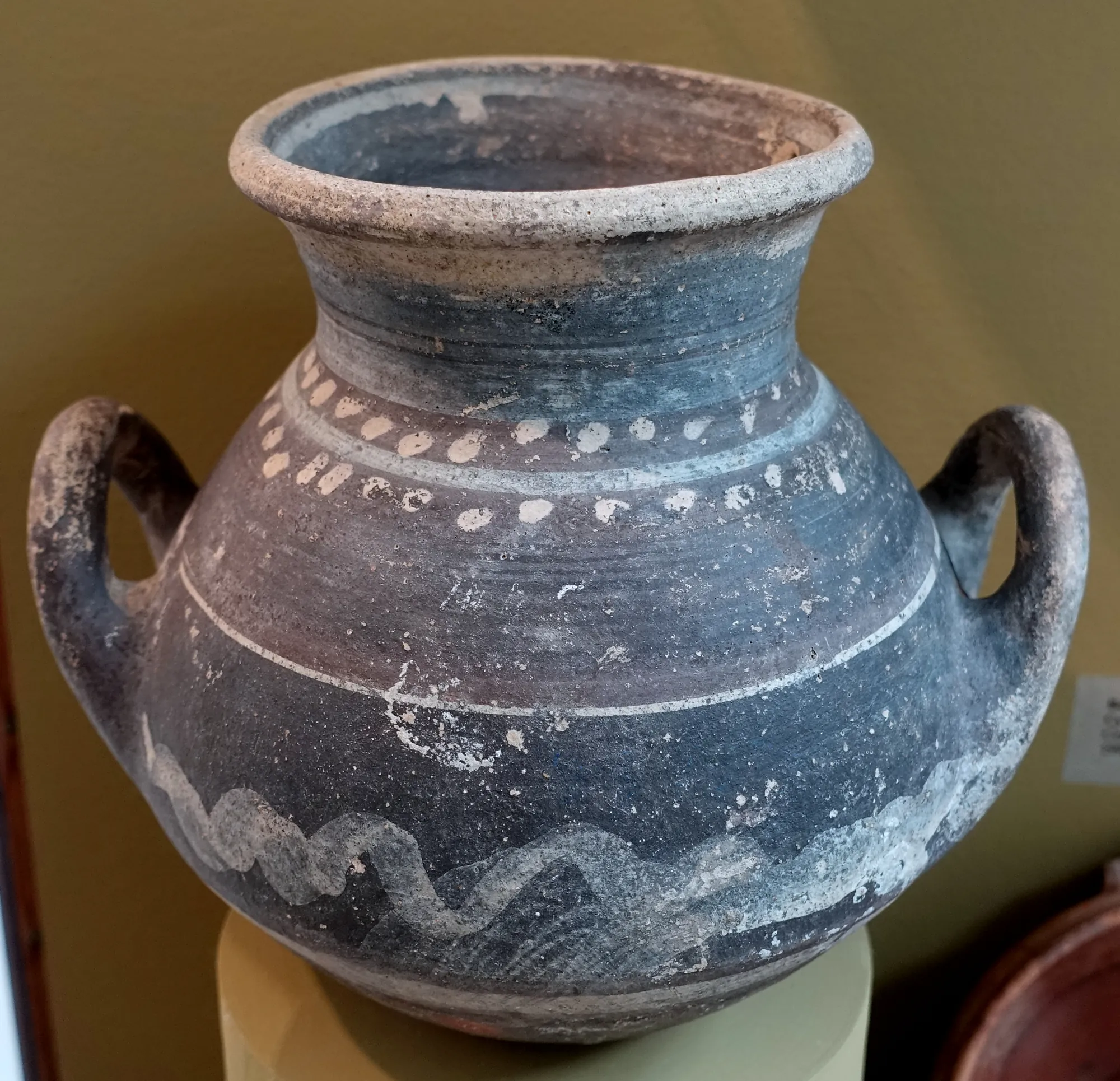 A two-handled storage krater with a dark surface decorated in white dots, bands and a wavy line