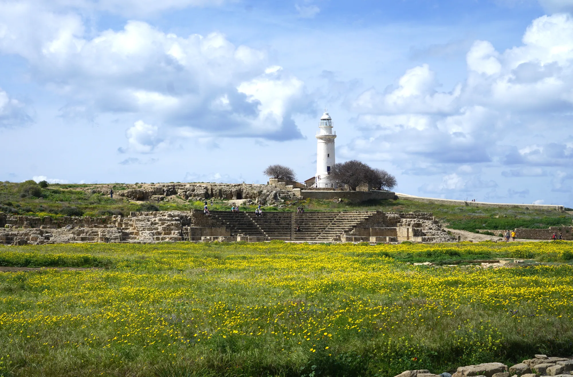 The odeion and the lighthouse hill seen across the open ground of the archaeological park in spring. Photo: Arjuno3, CC BY 4.0, via Wikimedia Commons, cropped.