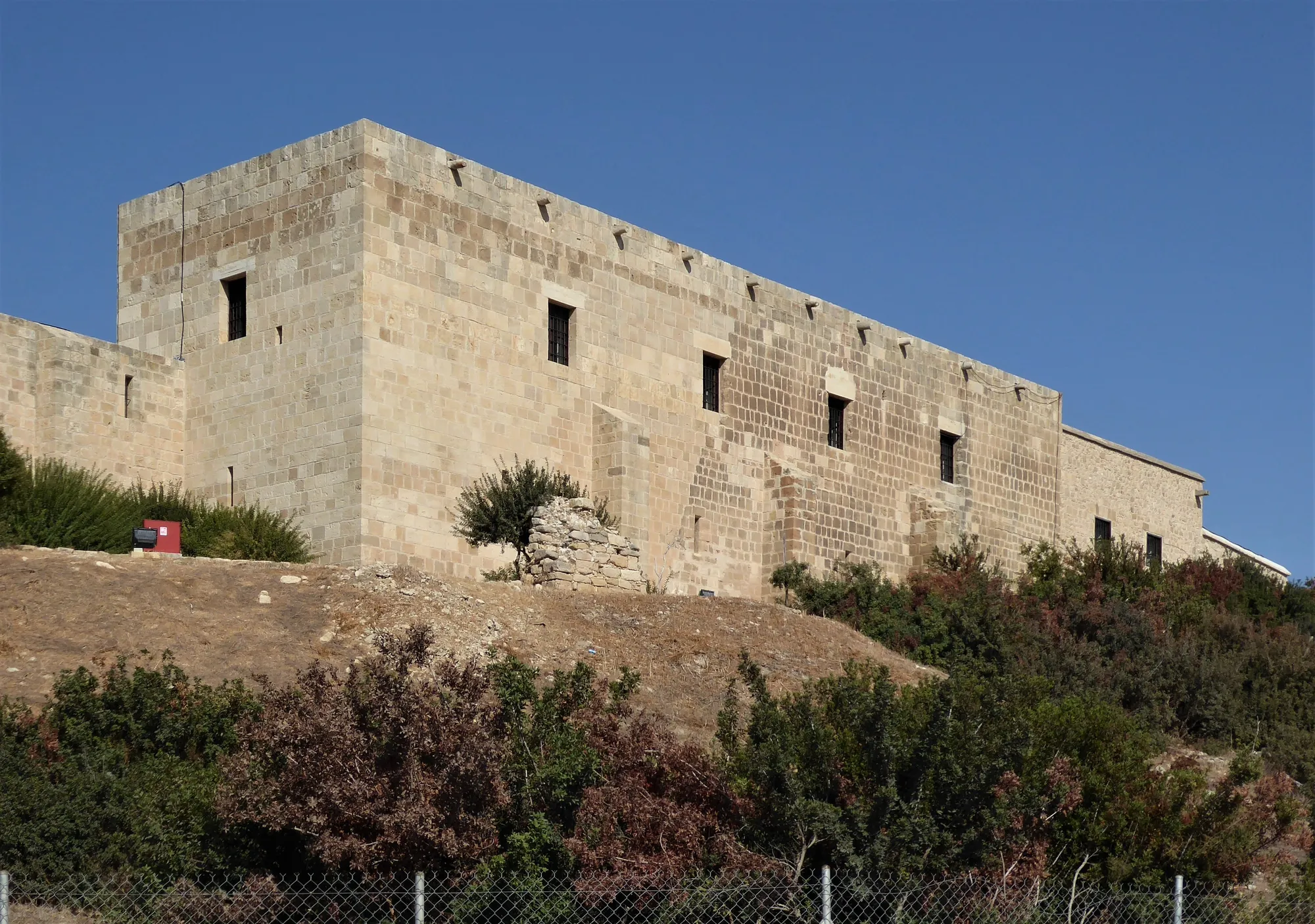 Rectangular stone building with small windows on a low mound, seen from below