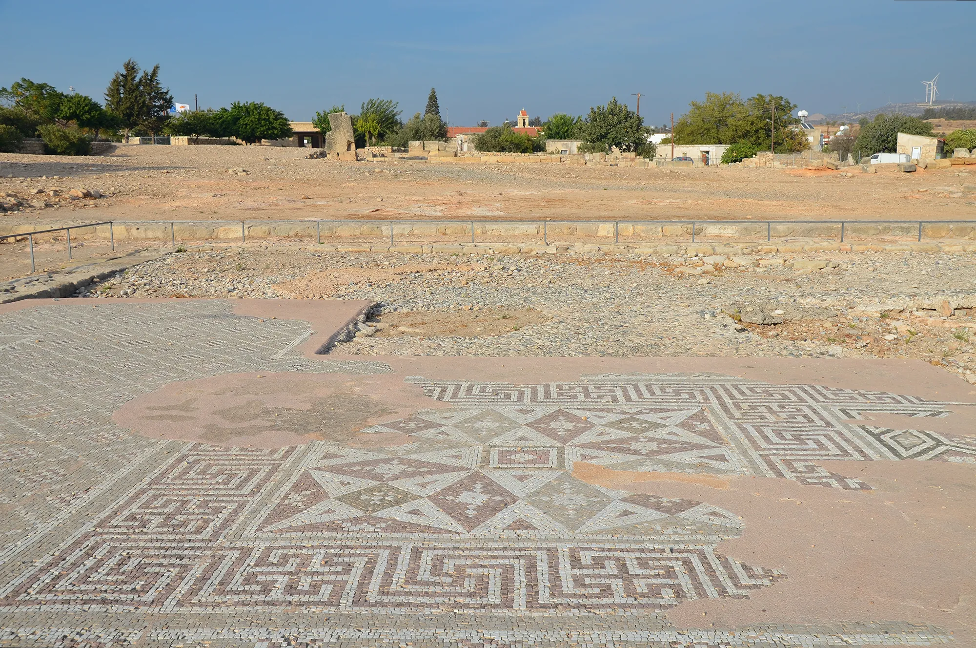 Geometric mosaic floor in the Roman buildings of the sanctuary of Aphrodite at Kouklia, with the village behind. Photo: Carole Raddato, CC BY-SA 2.0, cropped