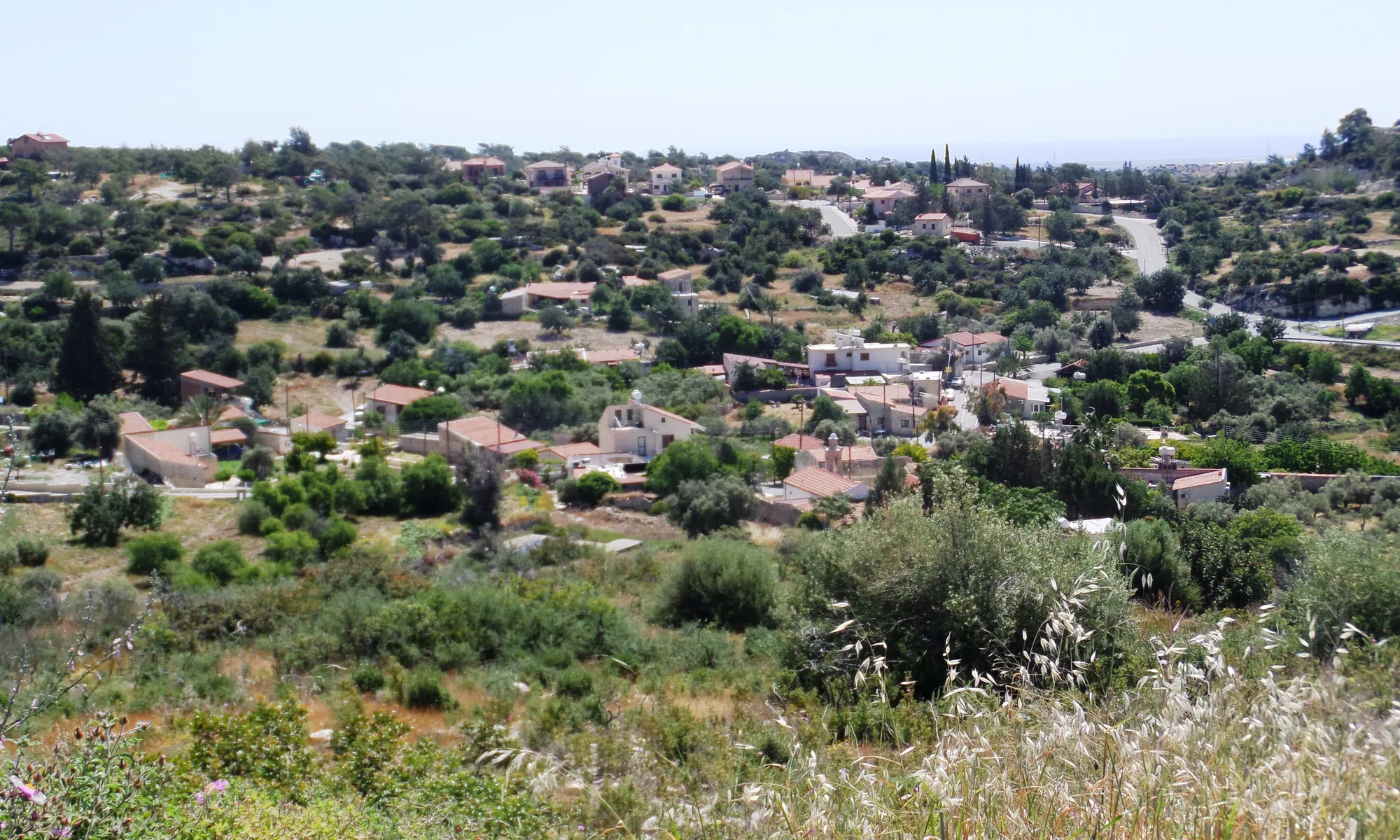 The modern village of Sotira among low wooded hills, with the sea faint on the horizon; Teppes and Kaminoudhia lie at the edge of the village and cannot be picked out in this view. Photo: Xaris333, CC BY-SA 4.0, via Wikimedia Commons, cropped